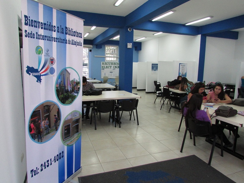 Estudiantes en mesas dentro de una biblioteca